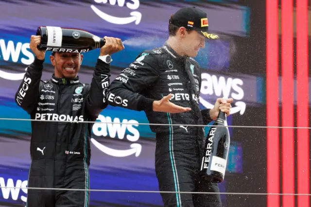 Lewis Hamilton pours champagne on George Russell on the Spanish podium