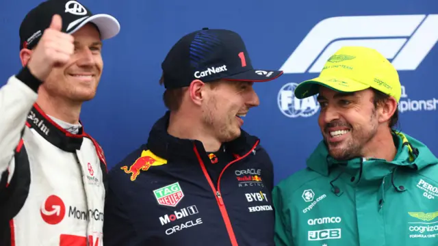 Nico Hulkenberg gives a thumbs up as Max Verstappen and Fernando Alonso smile at each other