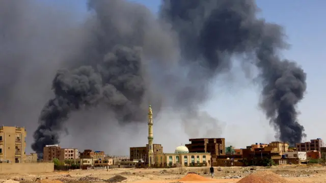 man walks while smoke rises above buildings after aerial bombardments during clashes between the paramilitary Rapid Support Forces and the army in Khartoum North, Sudan, May 1, 2023. REUTERS