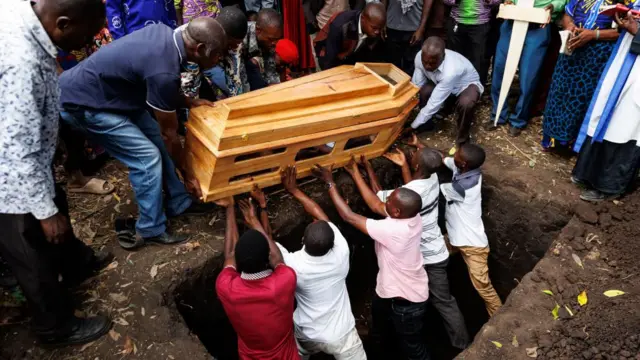 People lower a coffin into a grave during the funeral for one of the victims of an attack at a school, in Mpondwe, Uganda, 18 June 2023