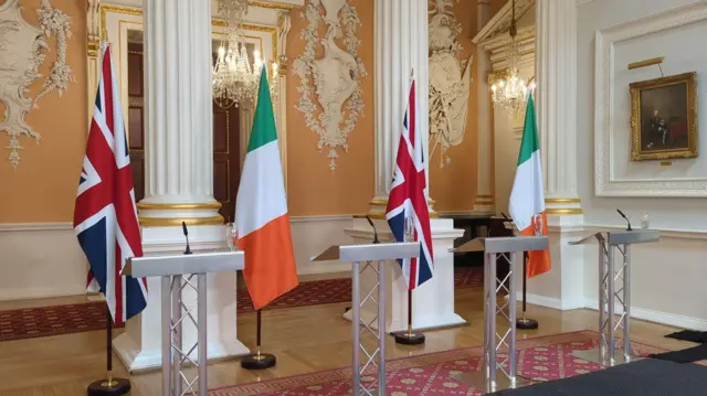 Union flag and Irish tricolour fly in the room where the press conference will take place