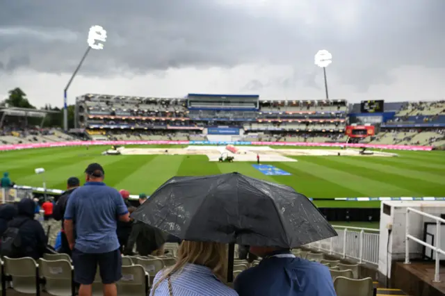 Spectators under umbrellas as rain falls at Edgbaston