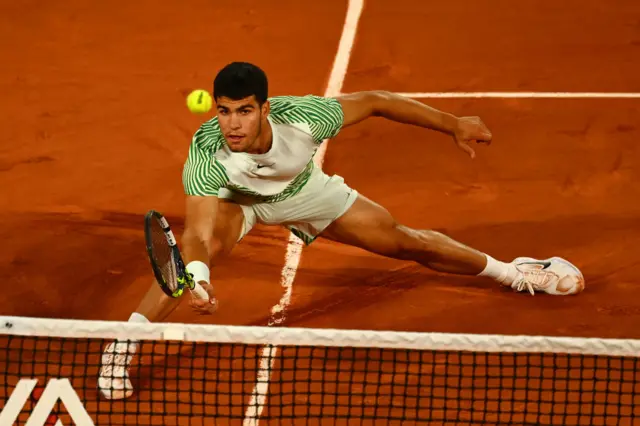 Carlos Alcaraz slides to reach a ball
