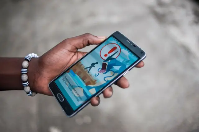 A man in Nigeria looks at Pokemon Go on his phone.