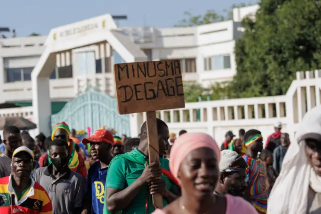 An attendee holds a placard translating into "MINUSMA GO AWAY" during Malis Independence Day Celebrations and a march against United Nations Multidimensional Integrated Stabilization Mission in Mali (MINUSMA) in Bamako on September 22, 2022.