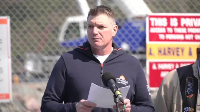 Sean Leet gives a press conference standing behind a microphone holding a piece of paper