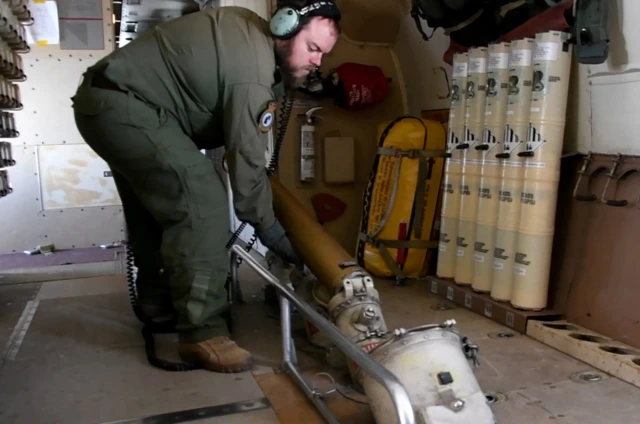 A crew member of a Royal Canadian Air Force CP-140 Aurora maritime surveillance aircraft of 14 Wing drops sonobuoys