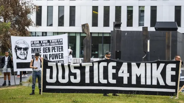 People hold a banner reading "Justice for Mike" before the verdict of six police officers accused of homicide charges for the death of Mike Ben Peter, a 39-year-old Nigerian in March 2018, in front of the criminal court in Renens, near Lausanne, Switzerland - 22 June 2023