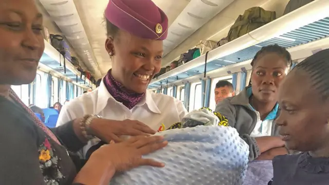 A railway attendant holding the new-born alongside the mother and those who had assisted in the birth - 21 June 2023