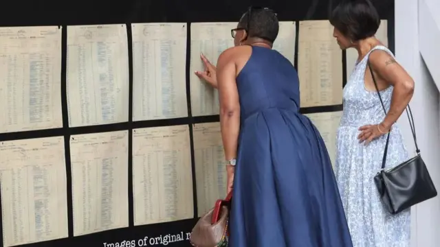 Visitors view images of the original passenger list at an exhibition space alongside the dock