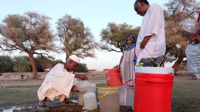 A man fills containers with water after citizens dig small holes at the shore to get pure water at the banks of the White Nile as clashes between the RSF and army continue in Khartoum, Sudan - May 2023