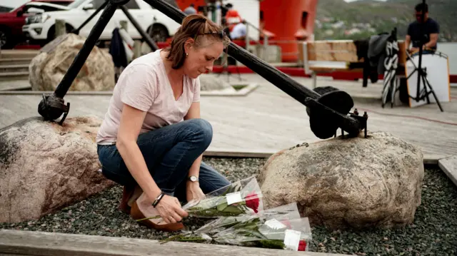 Roses are laid by a woman in St John's in tribute to the Titan passengers