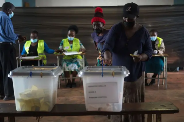 A woman casts a ballot on behalf of elderly woman whom she assisted to vote during a by-election at Amaveni Hall pollingstation on March 26, 2022