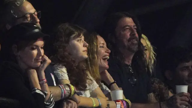 Guests, including Dave Grohl (4th right) watch Guns N' Roses performing on the Pyramid Stage