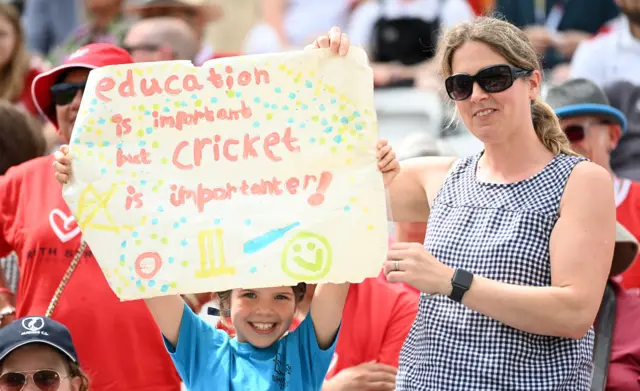 A kid holds up a poster at the women's Ashes Test