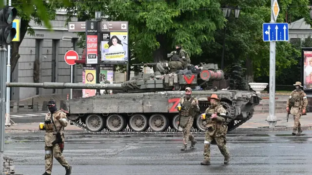 Fighters of Wagner private mercenary group cross a street as they get deployed near the headquarters of the Southern Military District in the city of Rostov-on-Don