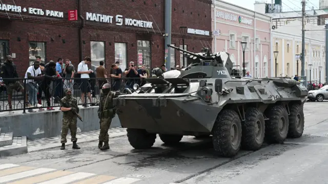 Fighters of Wagner private mercenary group stand next to an armoured vehicle in a street in the city of Rostov-on-Don