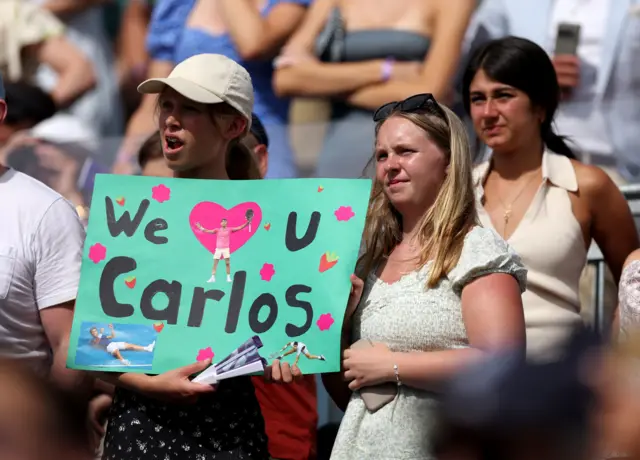 Fans with 'we love you Carlos' sign at Queen's