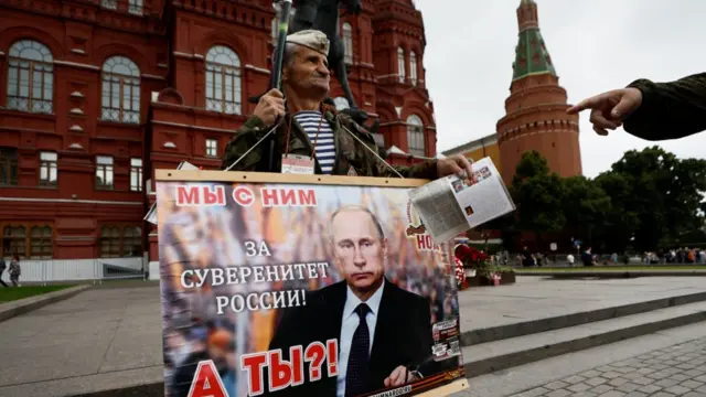 A supporter of Vladimir Putin stand with a photo of the Russian president on Moscow's Red Square. Photo: 24 June 2023