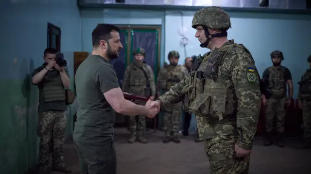 Volodymyr Zelensky shakes hands with a Ukrainian solider