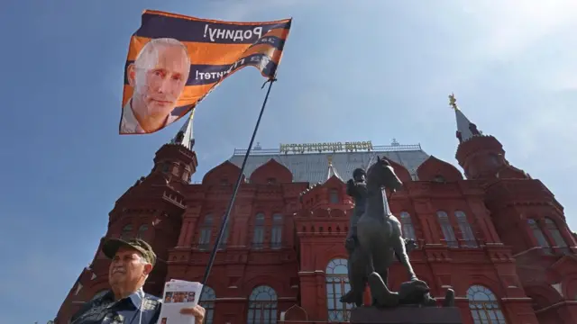 A member of the National Liberation Movement (NLM) holds a flag with a portrait of Russian President Putin reading 'For Motherland, For Sovereignty, For Putin' during a single picket in support of the Russian President in front of the monument to Marshal Zhukov on Manezhnaya Square, outside the Kremlin in Moscow, Russia, 25 June 2023.