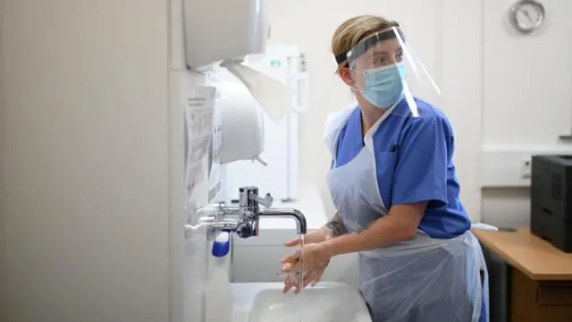 Nurse Ashleigh Smith wearing personal protective equipment (PPE) washes her hands at work at the Littlefield practice at Freshney Green Primary Care Centre in Grimsby