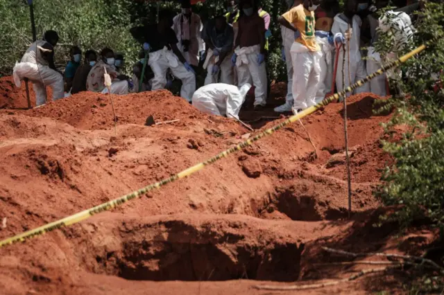 Workers digging to exhume bodies