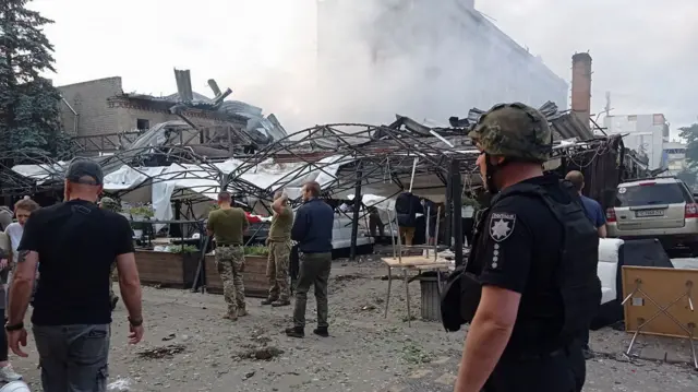 Police and soldiers stand by blown up buildings