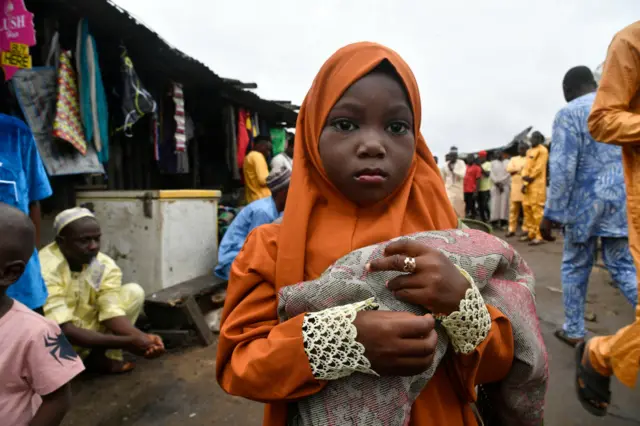 A young girl holds mat as she arrives to attend Eid Al-Adha prayers along the road at Ibafo in Ogun State, southwest Nigeria,