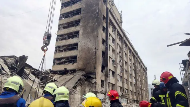 Rescue workers look at a heavily damaged building