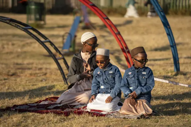 Children join their parents as they perform the Eid Al-Adha prayer at a public park in Johannesburg, South Africa