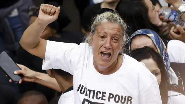 Nahel's mother Mounia cries and raises her fist in the air during a march for her son