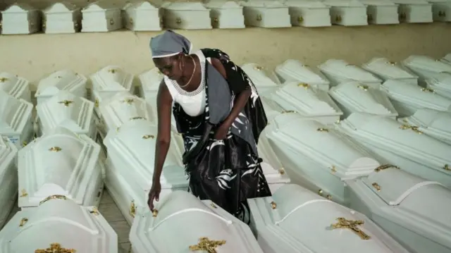 A survivor of Rwanda's 1994 genocide opens the coffins which contain remains of victims at the Nyanza Genocide Memorial ahead of a mass burial in Kigali -May 2019.