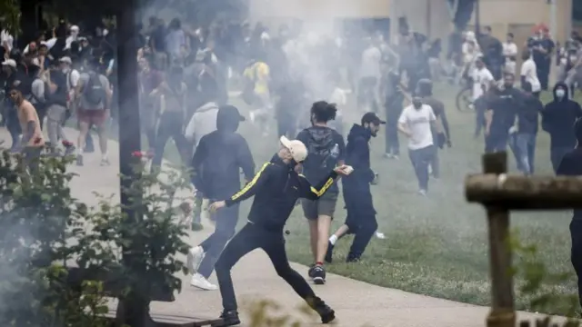 A protester throws a rock during clashes with French riot police following a march