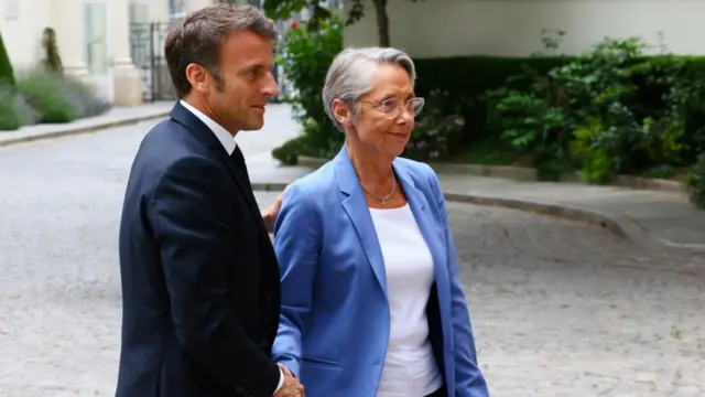 French President Emmanuel Macron shakes hands with French Prime Minister Elisabeth Borne as he arrives to attend a government emergency meeting