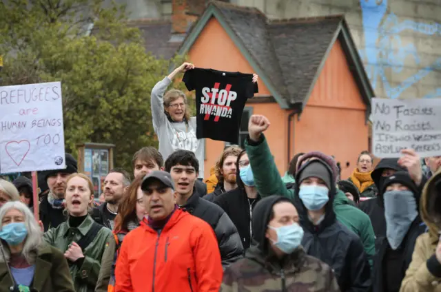 Protesters in support of refugees hold signs of support outside the Novotel, one holds a Stop Rwanda t-shirt on March 18, 2023 in Ipswich, United Kingdom.