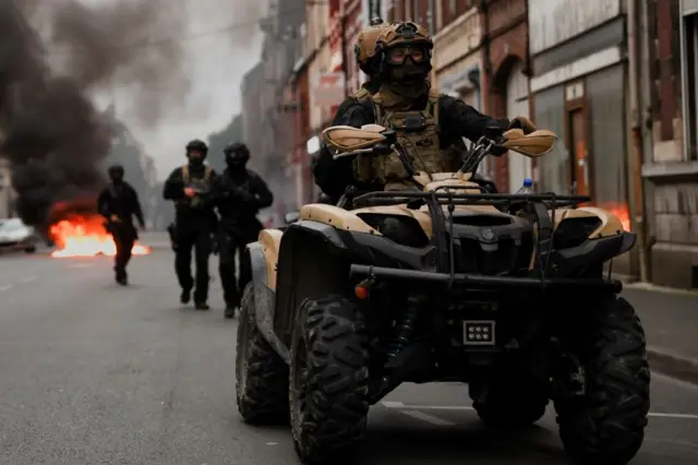 Officers ride a vehicle during riots in Lille, France