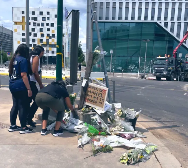 People laying flowers against a road sign