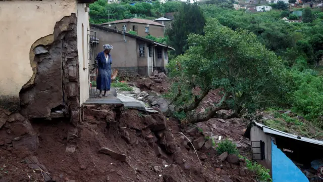 A woman stands at her front door after heavy rains caused flood damage in KwaNdengezi, Durban, South Africa, April 12, 2022