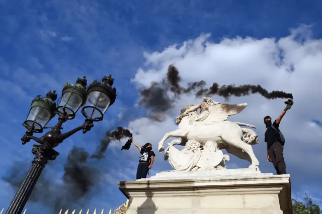 Demonstrators hold up smoke flares during a protest in Paris