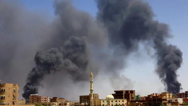 A man walks while smoke rises above buildings after aerial bombardment, during clashes between the paramilitary Rapid Support Forces and the army in Khartoum North, Sudan, May 1, 2023