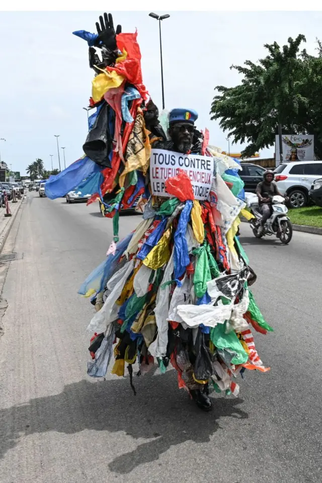 A man dressed in plastic waste walks down a street during the 50th World Environment Day celebrations in Abidjan on June 5, 2023