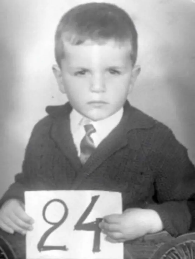 Ange Postecoglou as a 5-year-old holding the number 24 place card
