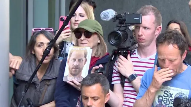 A woman holds up a copy of Prince Harry's book