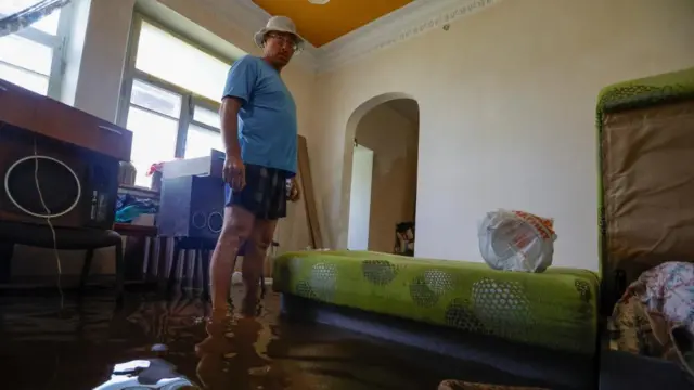 A man stands in floodwater inside a home