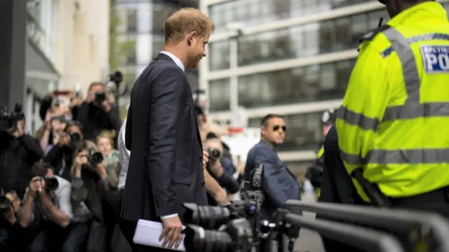 Prince Harry leaving court in front of a pack of photographers