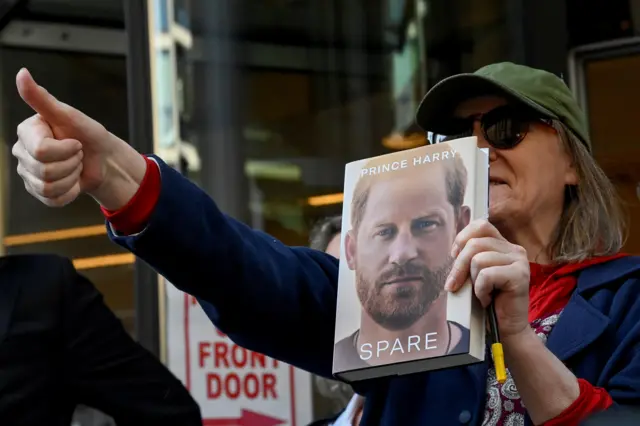 A supporter of Britain's Prince Harry gives a thumbs up outside the Rolls Building of the High Court in London