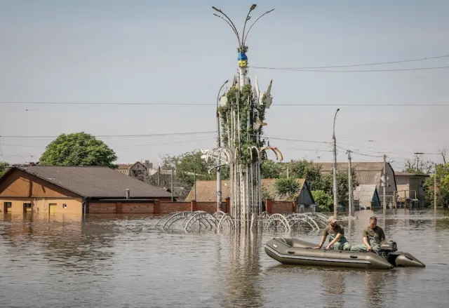 Volunteers sail on a boat during an evacuation of local residents from a flooded area after the Nova Kakhovka dam breached