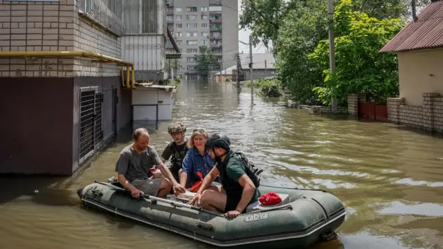 Volunteers evacuate local residents from a flooded area of Kherson