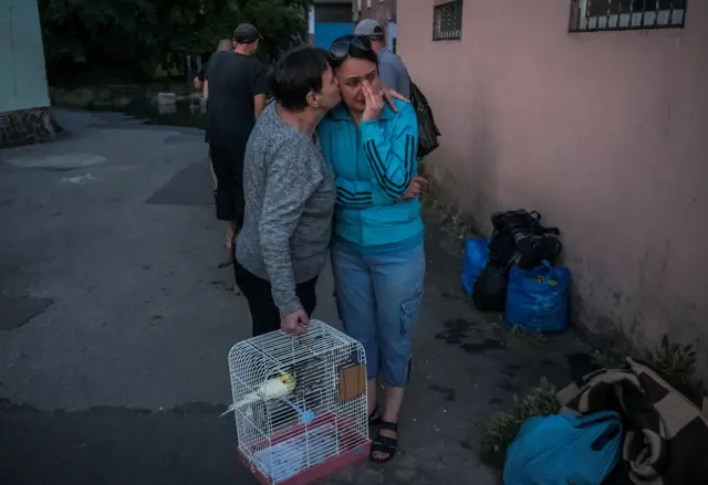 Woman cries as she carries possessions and pets out of her home